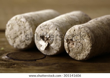 Closeup of three beige grained used small wine bottle stoppers or corks lying close to each other on wooden table top, horizontal picture