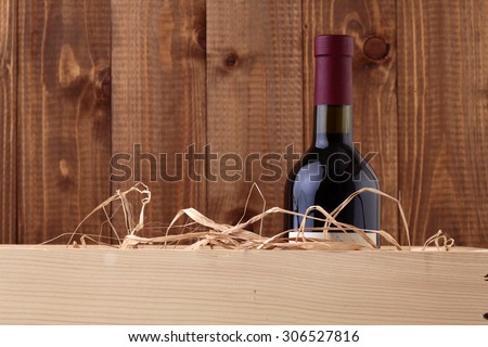 One glass wine corked new bottle full of alcohol red beverage wrapped in straw standing in box on wooden wall background copyspace, horizontal picture