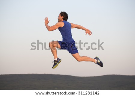 Full length side view of one muscular athlete sactive runner sportsman with brunette hair in blue sportswear in flight running outdoor on white background, horizontal picture