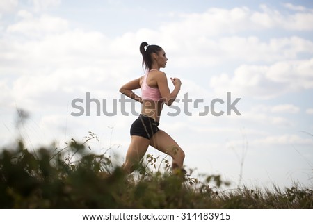Full length one sexy slim young brunette active girl with straight beautiful body in sportswear on morning running outdoor side view on cloud blue sky background, horizontal picture