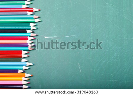 Palette set of colorful sharp pencils brown red yellow blue green violet pink purple lilac grey black white and orange colors lying in row on blackboard studio background copyspace, horizontal picture