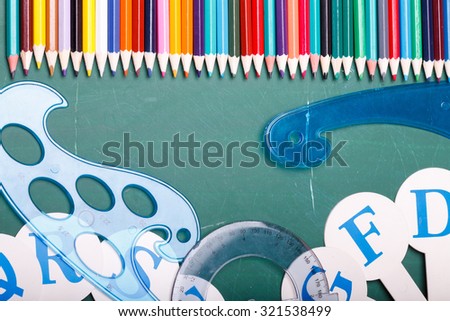 Palette set of colorful sharp pencils brown red yellow blue violet pink purple lilac grey black white and orange colors lying in row with other school tools on green background, horizontal