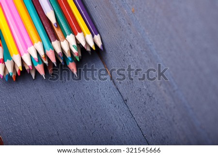 Palette set of colorful sharp pencils brown red yellow blue violet pink purple lilac grey black white and orange colors lying on wooden background copy space, horizontal picture