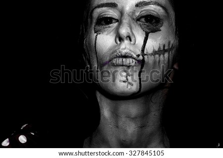 Portrait closeup view of one halloween holiday celebration character young woman with spooky painted face of zombi looking forward black and white, horizontal picture