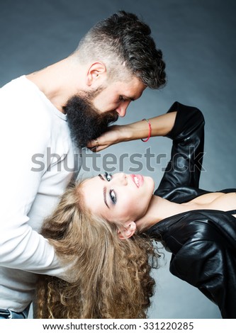 Portrait closeup couple of long-haired young sensual woman back arched touching beard of man with moustache bent over girl face holding hair grey background, vertical picture