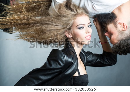 Portrait closeup couple of long-haired young sensual woman looking in camera touching beard of man with moustache hung over girl face to face grey background, horizontal picture