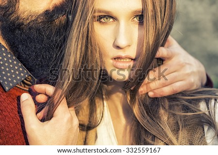 One beautiful stylish tender couple of young woman and senior man with long black beard embracing close to each other outdoor in spring sunny day, horizontal picture