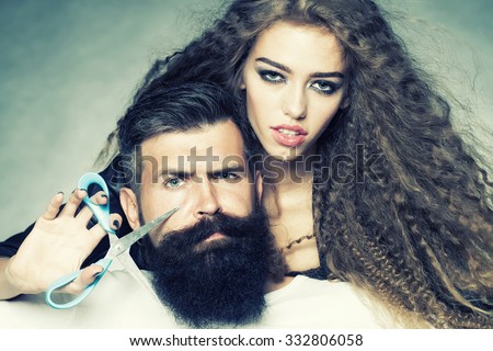 Closeup view on one attractive stylish emotional couple of young woman and senior man with long black beard drinking blue cocktail in glass with straw and orange slice sitting indoor, vertical photo