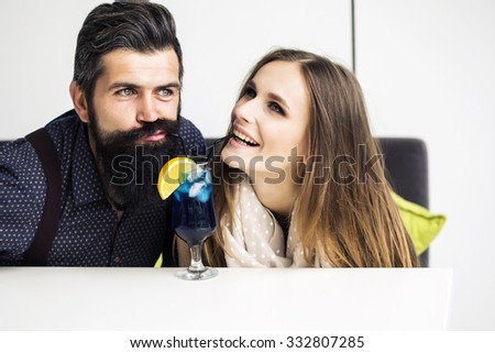 One beautiful stylish emotional couple of young woman and senior man with long black beard embracing sitting close to each other indoor in cafe, horizontal picture