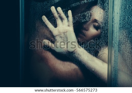 young couple of naked woman and man taking shower with water drops embracing in passion with wet bodies with hand on glass