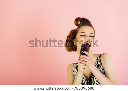 Woman singer with stylish retro hair and makeup. Girl in glasses sing in microphone. Beauty and vintage fashion. Pin up young girl on pink background, radio. Music, look and retro style, pinup.
