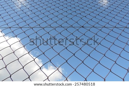 Metal mesh wire fence with cloud and blue sky background
