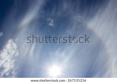 Shining sun with a corona and a blue sky and wispy cirrus clouds.