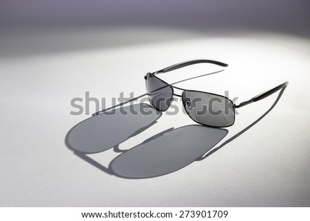Pair of sunglasses lit from behind creating an interesting shadow of the glasses. Isolated on a white background.