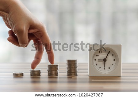 Hand with fingers business man putting on coin and looking for saving money, collect money with earning bank deposit interest and take time. Business ideas concept with blurred background