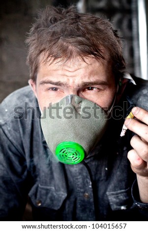 Portrait of dirty worker in gas mask smoking cigarette