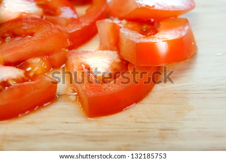 Sliced tomato on wooden board on white background