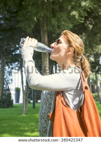 a woman with a bottle in hand in Sunny weather