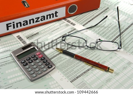 file folder marked with Finanzamt - in german: finance office - and tax form with pen, glasses and calculator