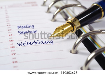 business calendar with fountain pen marked with meeting, seminar and education, in german: Weiterbildung