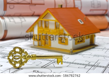 model house and blueprints with golden ancient key