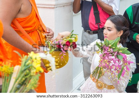 Saraburi,Thailand - July 31 : beautiful woman giving flower alms to buddhist monks in annual festival of flower alm to buddhist on 31 July 2015