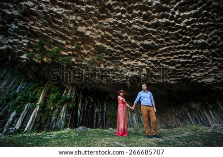 young couple holding hands on a fantastic background of rocks in