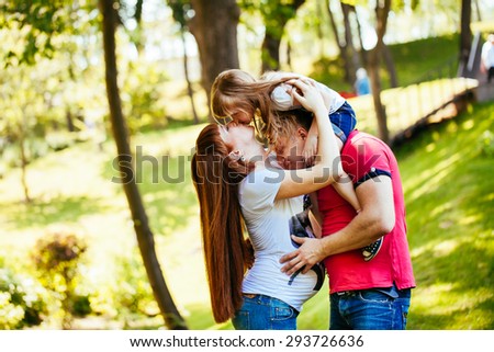 Young and beautiful family in the park, a pregnant mother, father, daughter