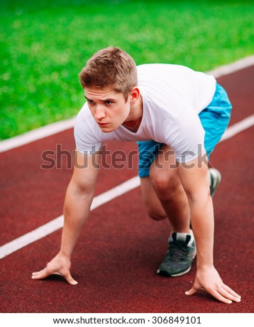 Athletic man on track starting to run. Healthy fitness concept with active lifestyle.
