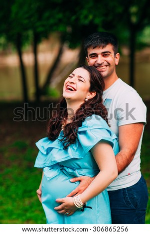 Beautiful pregnant couple relaxing outside in the park.