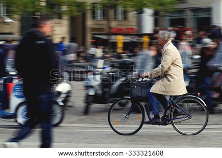 Amsterdam,Netherlands - October 30, 2015: Panning shot of a man on bicycle in the Dam Square in Amsterdam, Netherlands
