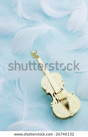 Golden violin with white feather on blue background