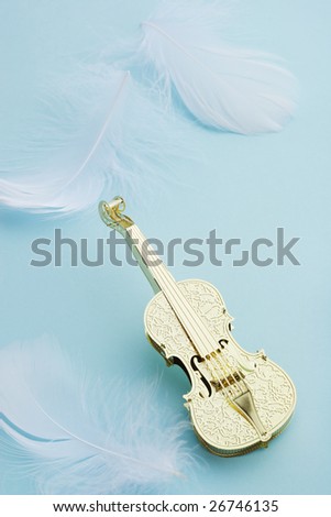 Golden violin with white feather on blue background