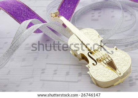 Golden violin with ribbons on music note background