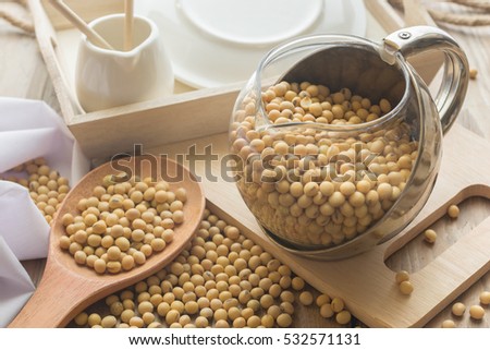 Jar of soybean on wood table with soybean in wood spoon.