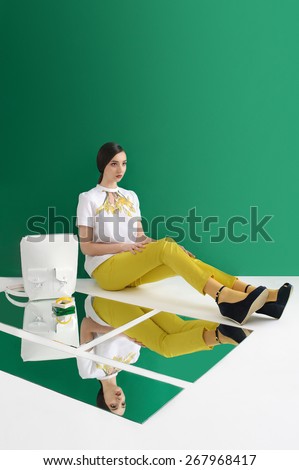 Model posing in yellow trouses and white blouse with print