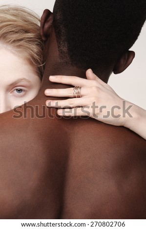 Beautiful young girl looks from a back of african american man