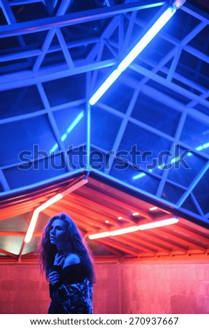 Androgynous beautiful young man as a beautiful woman in night city with neon lights on background