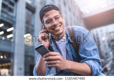 Man Sitting Listening Music Earphones Concept. Cheerful young guy listening the music.