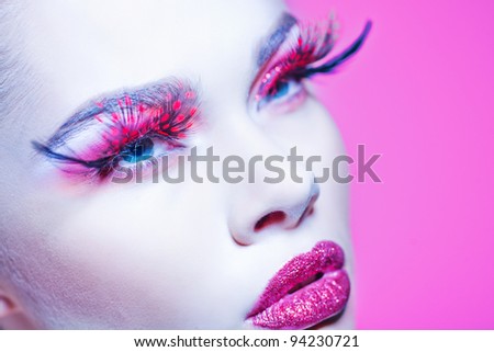 Close-up of beautiful woman face with Creative Fashion Art make up and eyelashes.  Studio