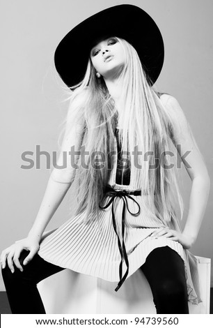 Blond woman  with long beautiful hair and smoky eyes in a hat. Studio