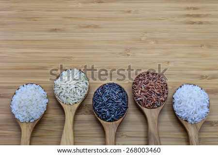 Variety of rice in wood spoon on wood background. From left: Japanese rice, pounded brown rice, forbidden rice (rice-berry), pounded red rice, jasmine rice