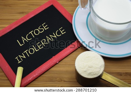 Lactose intolerance word on chalk board with a cup of milk and  milk powder