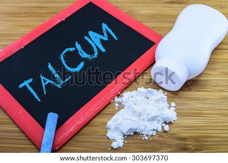 Talcum written on chalkboard with baby talcum powder and container on wood background