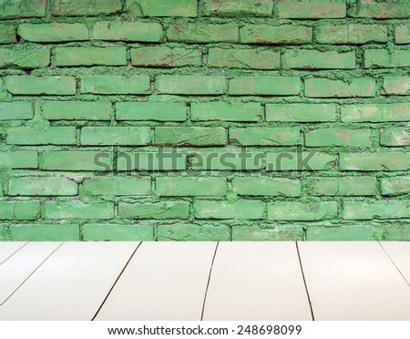 Grungy textured green brick wall with white wooden floor inside