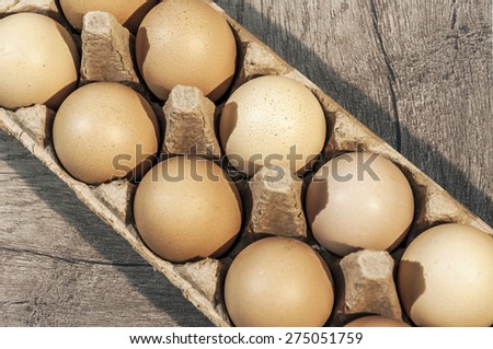 Ten brown eggs in a carton package on a wooden table, eggs on table