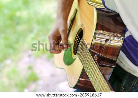 Young guitar player playing song outdoor in park
