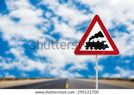 Railroad Level Crossing Sign without barrier or gate ahead the road with cloudy blue sky