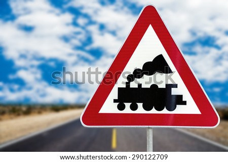 Railroad Level Crossing Sign without barrier or gate ahead the road with cloudy blue sky