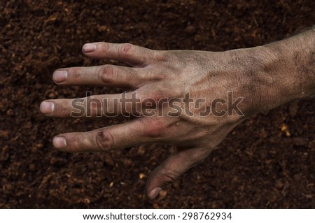 Farmer\'s rough hand isolated on fertile soil